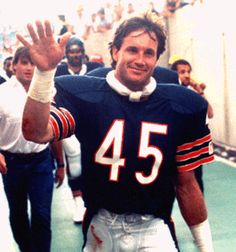 a football player is holding his hand up in the air as he walks with other players behind him