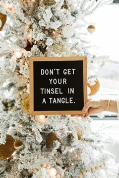 a person holding up a sign that says don't get your tinsel in a tangle