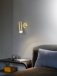 a lamp that is on the side of a wall next to a bed with pillows