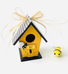 a small yellow birdhouse next to a bee toy