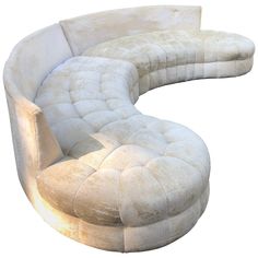 a curved white couch sitting on top of a white floor