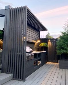 an outdoor kitchen is built into the side of a deck with potted plants on it