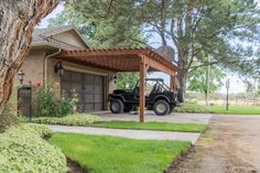 a black jeep parked in front of a house under a pergolated covered driveway