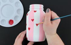 someone is painting a jar with hearts on it