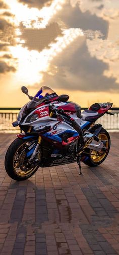 a motorcycle parked on the side of a brick road next to a body of water