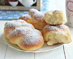 powdered sugar covered donuts on a plate next to a cup