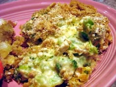 a pink plate topped with broccoli covered in cheese next to a slice of tomato