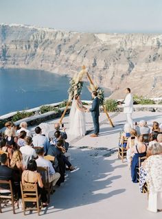 a couple getting married at the top of a mountain overlooking an ocean and mountains in the background