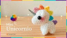 a small crocheted unicorn is sitting on a wooden table with colorful lights in the background