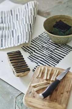 a wooden cutting board sitting on top of a table next to a bowl and knife