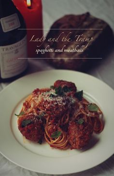 spaghetti and meatballs on a plate next to a bottle of wine