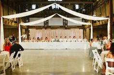 a group of people sitting at tables with white chairs