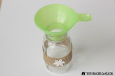 a glass bottle filled with sand and a green spoon