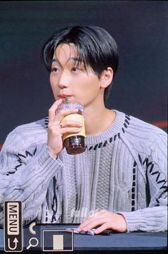 a man sitting at a table with a donut in his hand and a drink in his mouth