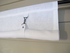 a close up of a white curtain with a metal hook attached to it's side