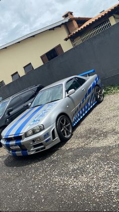 a silver car with blue stripes parked in a parking lot