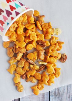 a paper cup filled with cereal on top of a wooden table next to a pile of nuts