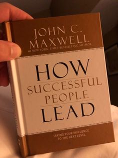 the book how successful people lead by john c maxwell is being held in front of someone's face