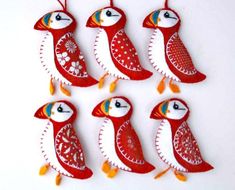 six red and white bird ornaments hanging from strings on a string with orange tassels