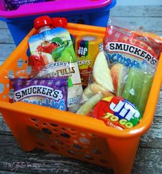 an orange basket filled with snacks sitting on top of a wooden table