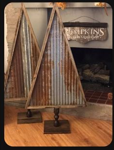 two metal christmas trees on wooden bases in front of a fireplace