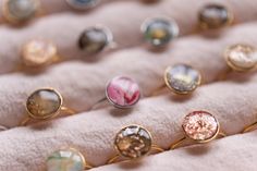 an assortment of rings sitting on top of a pink cushioned surface with gold flecks