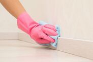 a person wearing pink gloves and holding a sponge on the edge of a white wall