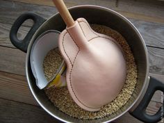 a leather heart shaped object in a pot with some spoons and an empty can