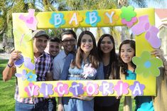 a group of people standing in front of a sign that says baby victoria with flowers on it