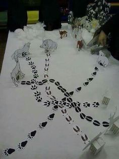 the table is covered with paper cut out animals and footprints on it's surface