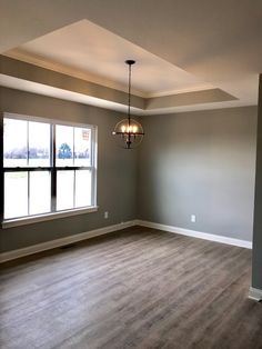 an empty room with hard wood floors and gray walls