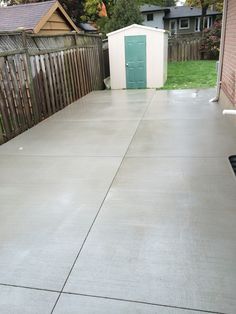 a concrete patio with a storage shed in the background