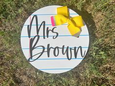 a paper sign that says, mrs brown with a yellow bow on it sitting in the grass