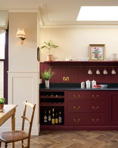 a kitchen with wooden floors and red cabinetry next to a dining room table in front of a window