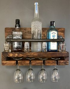 a wooden shelf with wine glasses and liquor bottles on it, hanging from the wall