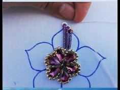 someone is stitching the beading on a flower ornament with beads and tassels