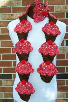 there is a crocheted scarf with cupcakes hanging from it's sides