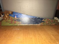 a skateboard is sitting on the floor next to a wooden board with an image of a lighthouse