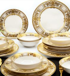 a table topped with lots of white and gold plates