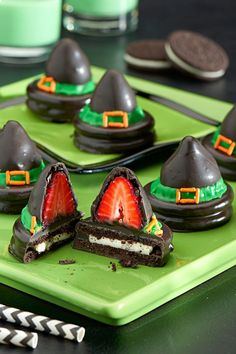 chocolate covered desserts with strawberries and witches hats on green plates next to silverware