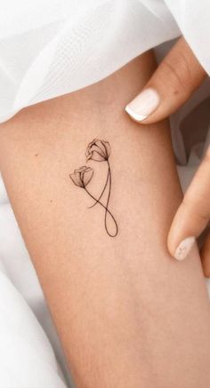 a woman's leg with a small flower tattoo on the left side of her thigh