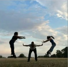 three people are jumping in the air with their hands out and one person is wearing jeans