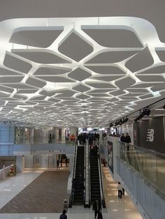 an escalator with people walking up and down it in a large building,