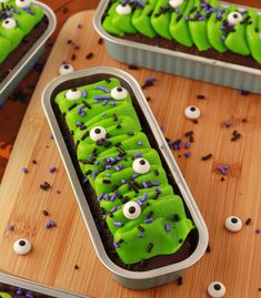 two tins filled with green frosting and sprinkles on top of a wooden table