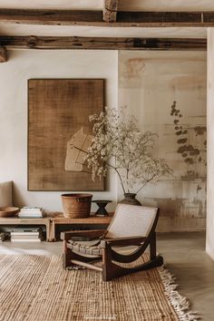 a chair and table in a room with paintings on the wall behind it that is decorated with wicker