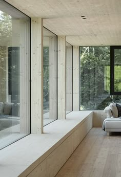 a living room filled with lots of windows next to a wooden floor covered in furniture