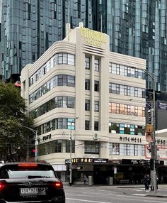 a car is driving down the street in front of a large building with many windows