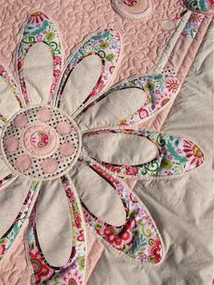 a close up of a quilted bed with a flower design on the center piece