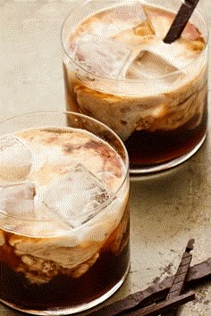 two glasses filled with ice sitting on top of a table