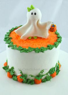 a white cake with orange and green frosting on it's side, decorated like a ghost